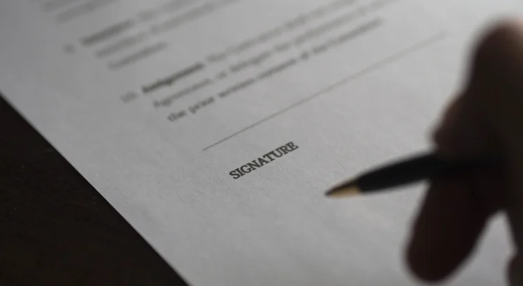 A pen hovering over the signature line of a printed contract