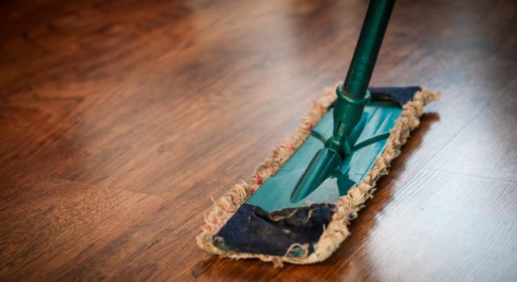 A flat mop cleaning a shiny wooden floor