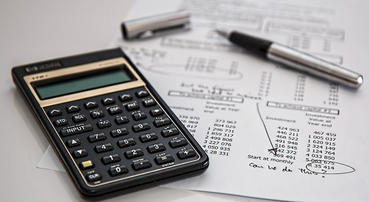 Calculator, pen, and financial paperwork on a desk.